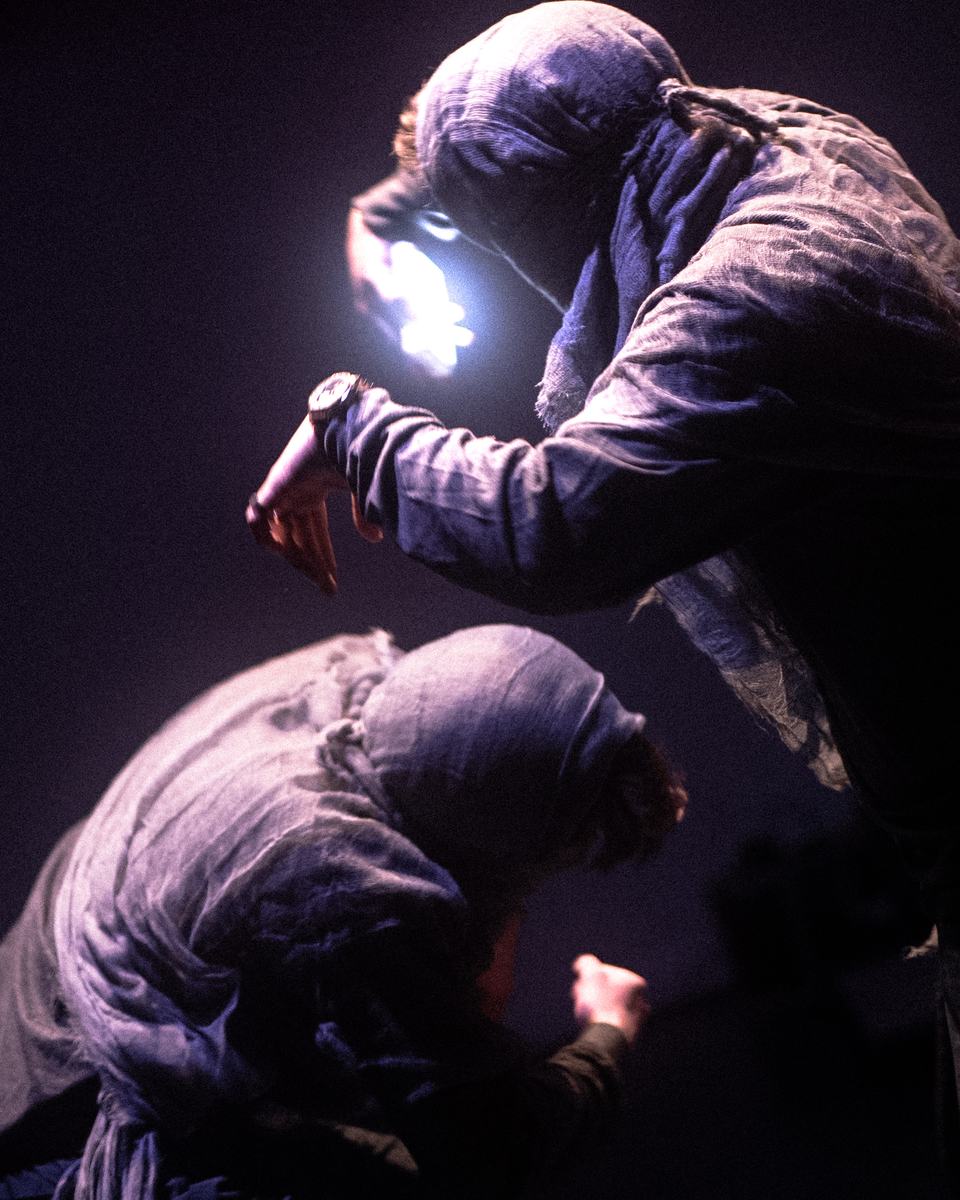 Hooded dancers holding a light