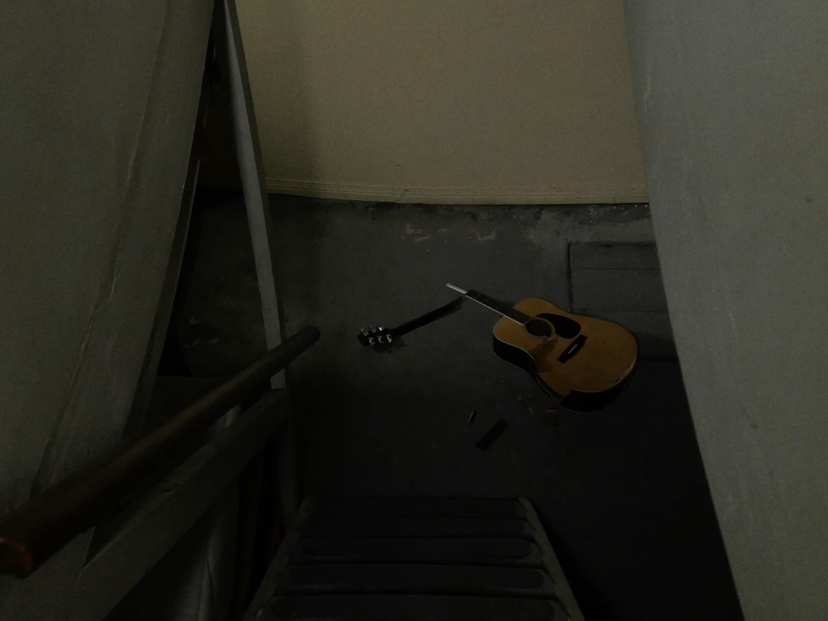 Frame from #nothinglastsforever: a guitar at the foot of a stairwell