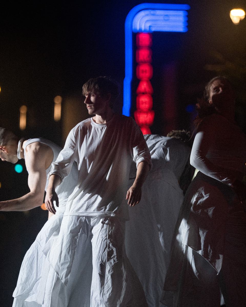 Dancers in white in front of the Broadway Theatre sign