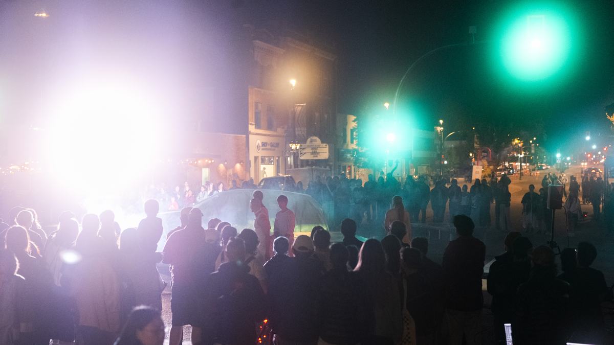 The crowd around the car under a green traffic light