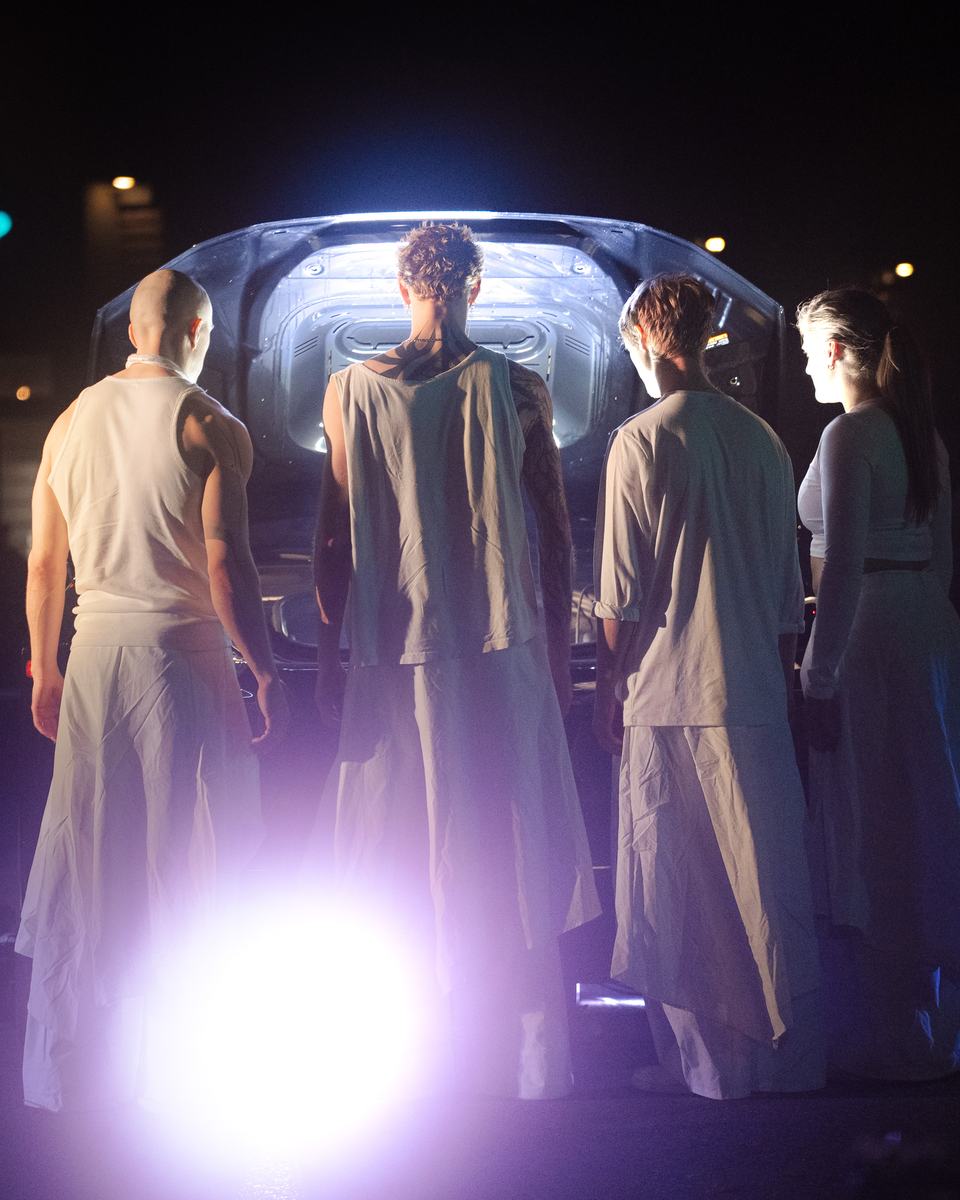 Dancers at the lit back of the car