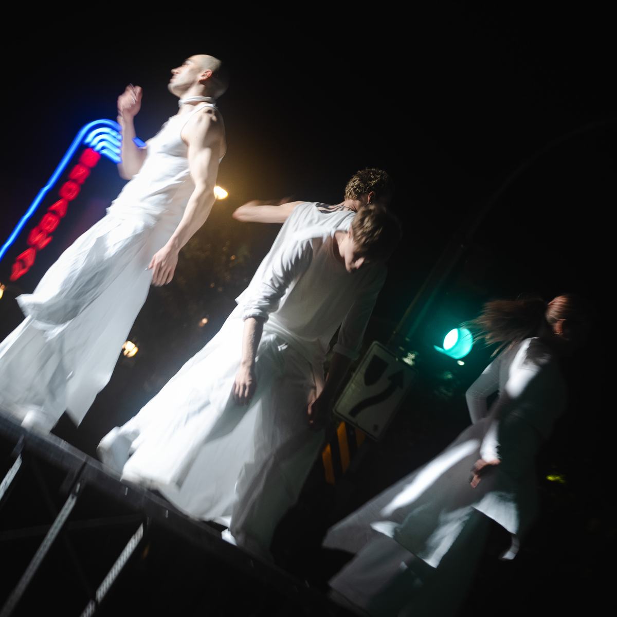 Dancers on a tilted platform under the Broadway Theatre sign