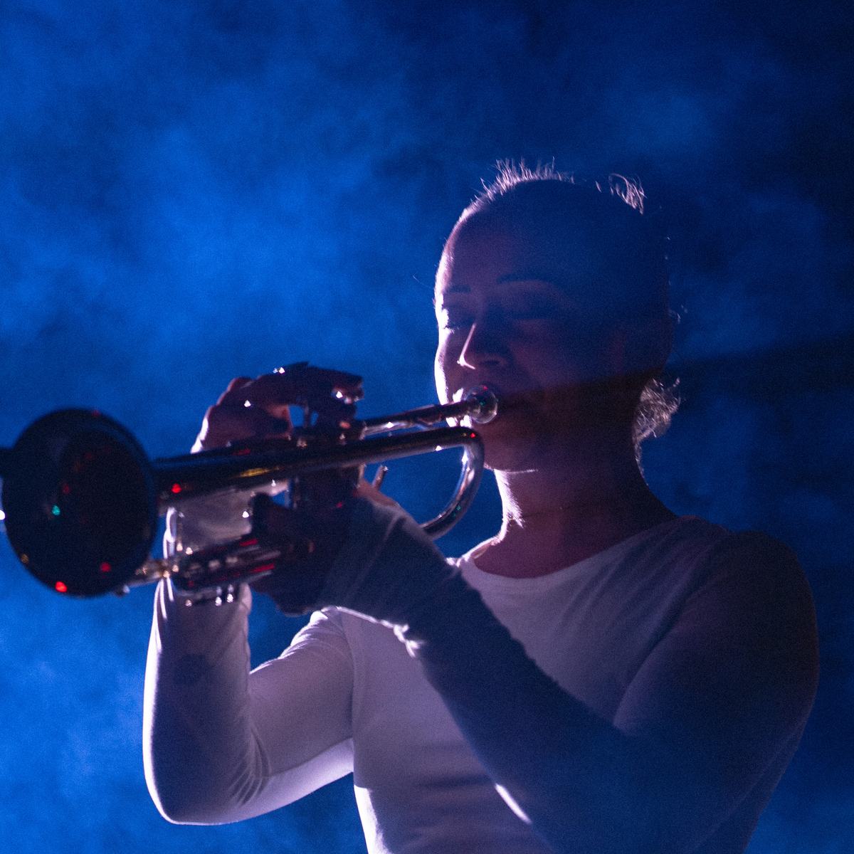 Briana Gillet playing trumpet in blue light